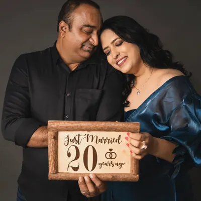 Celebrating a huge milestone! This couple commemorates their 20th wedding anniversary with a special studio photoshoot, holding a sign that reads "Just Married 20 years ago."