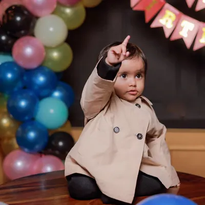 The birthday boy, Vasuki, pointing up as if to say "I'm one!". I focus on capturing these fleeting gestures and expressions that make for unforgettable first birthday photos.