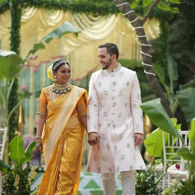 For Sam and Matt's wedding in Pune, we blended her South Indian roots with his Western background. Here they are, taking their first walk as a married couple, with the bride in a stunning traditional yellow saree and the groom in a classic embroidered sherwani.