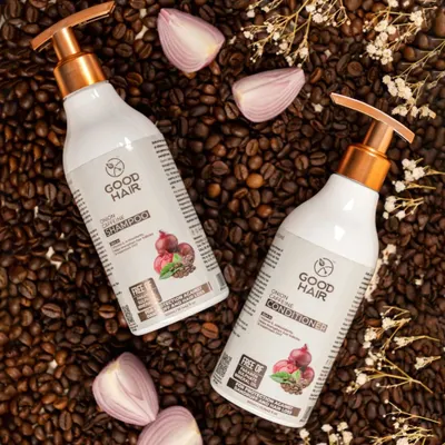 This top-down flat lay of shampoo and conditioner bottles is arranged on a bed of coffee beans with onion slices. This visually connects the products directly to their main ingredients, telling a clear story about the formula.