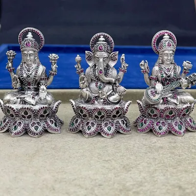 The complete set of our 925 silver Lakshmi, Ganesh, and Saraswati idols. The intricate stone work in ruby and emerald on the crowns and lotus bases highlights the divine details of each deity.