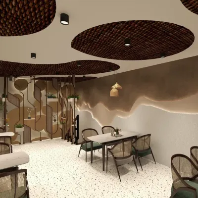 The main dining area of this Haldwani cafe features custom-designed ceiling panels with woven inserts, creating a unique, organic canopy. The space is furnished with cane-backed chairs and marble-topped tables on a bright terrazzo floor.