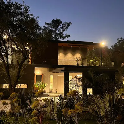 At night, the landscape lighting at "The One" residence transforms the home. Uplighting on the trees and soft lights within the garden beds create a warm, inviting glow that highlights the textures of the plants and the modern lines of the architecture.