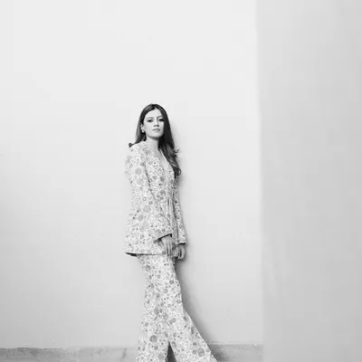 A striking, minimalist black and white portrait of the bride, Mouli, against a clean wall, her modern Sabyasachi pantsuit creating a powerful silhouette.
