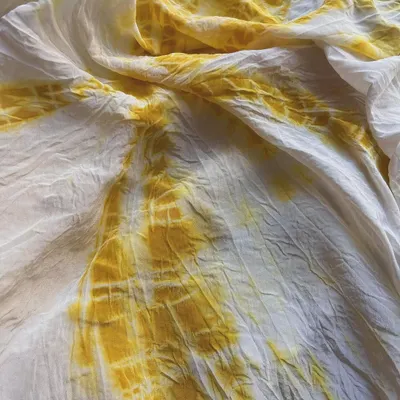 This beautiful yellow Mulberry Silk fabric was dyed with turmeric using a 10% mordant to ensure the color stays vibrant forever with easy care. The tie-dye technique creates a stunning, sunburst-like pattern.