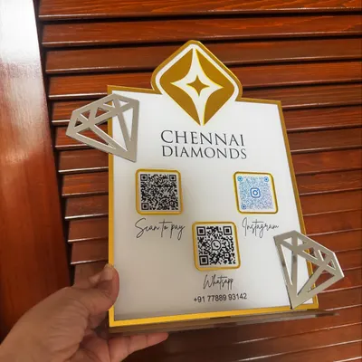 A hand-held view of the custom QR stand for Chennai Diamonds, showing the crisp engraving and the 3D effect of the logo and diamond cutouts.