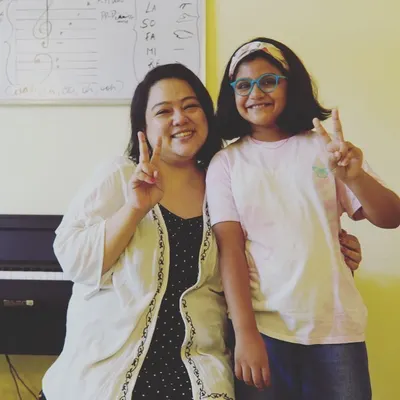 A happy moment with a student after a productive vocal session. The whiteboard behind us shows some of the music theory fundamentals we cover, like solfege and notation, which are essential for every singer and musician.