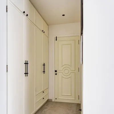 The master bedroom's walk-in wardrobe features clean, white paneled doors and elegant black handles, leading to a beautifully detailed bedroom door. This corridor is a perfect example of our focus on creating seamless and sophisticated transitions between spaces.