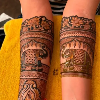 This design features large, decorated elephants as the main focus on the arms. The 'A' initial is also incorporated into the design on the wrist.