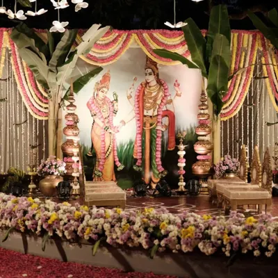 A traditional South Indian wedding stage setup at our ashram. The decor features banana leaves, marigold garlands, and brass lamps, with a beautiful illustration of a divine couple, creating a truly sacred ambiance for the ceremony.