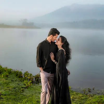 An intimate moment by a misty lake at dawn. The soft morning light and fog create an incredibly romantic and serene atmosphere for a couple photoshoot.