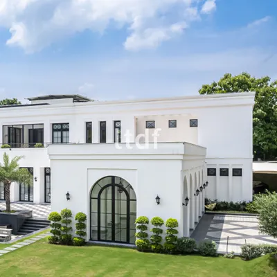 This view of the farmhouse highlights its refined elegance, with large French-style arched windows that flood the interior with natural light. The design balances contemporary simplicity with the grandeur of traditional architectural forms.
