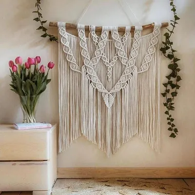 A large, elegant macrame wall hanging styled beautifully above a wooden side table with fresh tulips. This shows how my art can elevate a space and create a serene, boho-chic atmosphere.