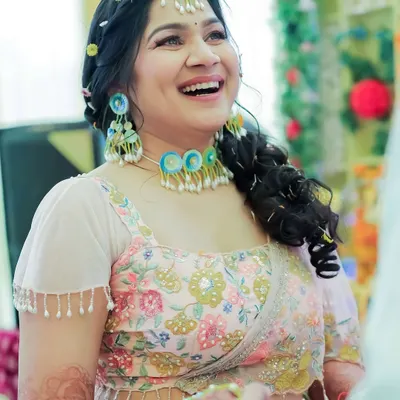 A close-up of the bride's happy face during her Haldi ceremony. The makeup is minimal and fresh, with a focus on rosy cheeks and a bright smile to match the festive vibe.