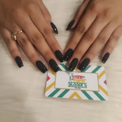 A full set of glossy black nails. This timeless and bold choice on medium-length coffin nails is always in style and adds a touch of sophistication to any look.