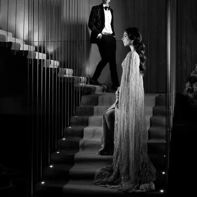 A dramatic black and white portrait of the couple on a staircase. This shot is all about style, mood, and creating a cinematic, high-fashion look for their engagement.