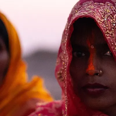 A close portrait of a woman during Chhath Puja in Bihar, her direct gaze and the traditional sindoor creating a powerful image of faith.