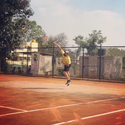 An adult male player leaps into a powerful serve during the Tennis360 Men's Open Tour.