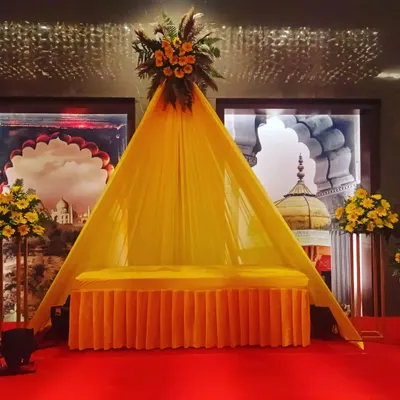 This is a special seating arrangement for a Haldi ceremony. I created a small, tent-like structure with yellow fabric and a floral top, providing a dedicated and decorated spot for the main rituals.