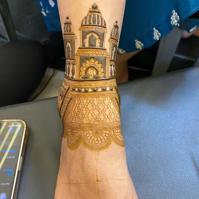 This foot mehndi features a detailed architectural design around the ankle, resembling a grand palace. The intricate jaal pattern covers the top of the foot.