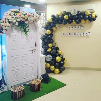 A modern take on retirement party decor. This organic balloon garland in a sophisticated black and gold palette adds a stylish touch to the celebration space, complemented by a decorative photo booth backdrop.
