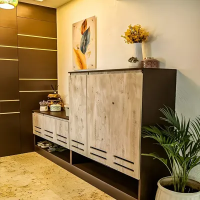 This entryway features a custom-designed shoe cabinet with distressed wood-finish doors. The unit provides both concealed and open storage for shoes, keeping the entrance neat and tidy.