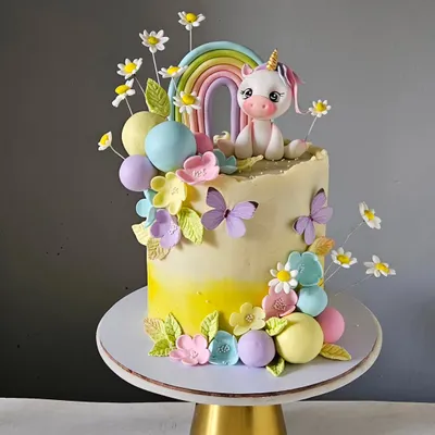 This magical unicorn cake is set in a pastel garden, complete with a rainbow, delicate sugar flowers, and fluttering butterflies. The unicorn figurine is hand-sculpted and sits atop a buttercream cake, making it a perfect fairytale centerpiece.