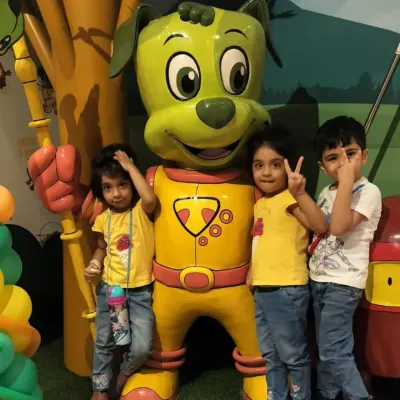 Three young friends pose with our main mascot, Tinga Dojo. These character interactions are a highlight for many of our visitors.