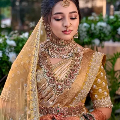 A close-up of Nischaya's regal Muhurtham makeup. The focus is on flawless skin, softly defined eyes, and intricate jewelry placement to create a look of pure South Indian royalty.