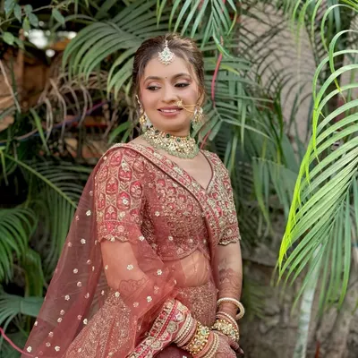 A beautiful bridal portrait showcasing a soft glam look with a focus on dewy skin and defined eyes, perfectly complementing her ornate red lehenga.