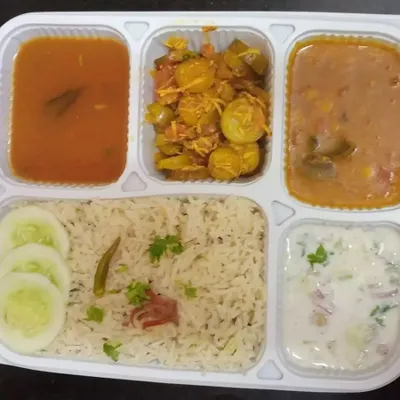 A classic North Indian vegetarian thali, perfect for a daily lunch subscription. It features rice, dal, a dry vegetable preparation, a light curry, and creamy raita, offering a complete nutritional profile.