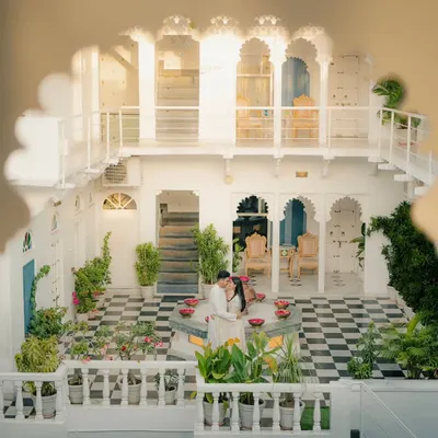 A wide-angle shot capturing the couple in a beautiful white courtyard in Udaipur. This image showcases the stunning architecture and creates a sense of privacy and grandeur.