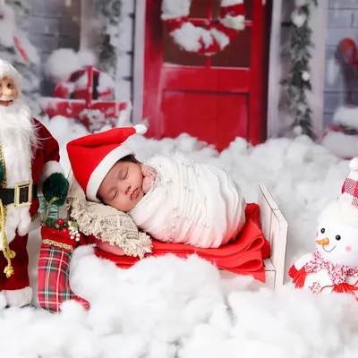 Your baby's first Christmas is a special milestone. Here, a newborn sleeps soundly in a sleigh, surrounded by a festive scene with Santa, a snowman, and a snowy backdrop.