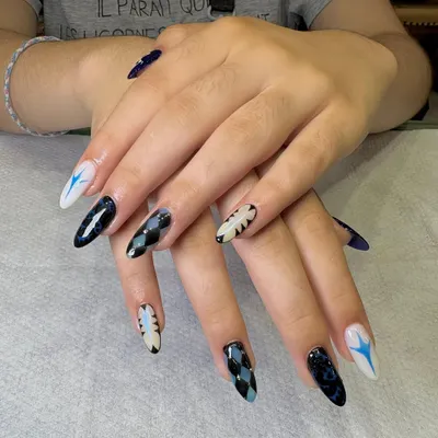 A bold and graphic nail art look for a client who wanted something unique. This set features a mix of patterns, including argyle, abstract flames, and starbursts, all in a striking black, white, and blue color palette.