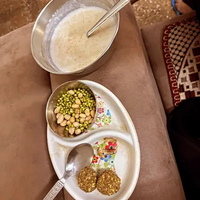 This is an example of a perfect high-protein morning breakfast to fuel your day. It includes oatmeal, protein laddoos, and sprouted mung beans with peanuts, totaling around 500 calories with 25 grams of protein.