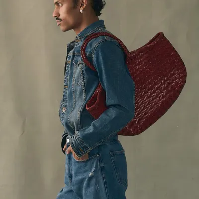A model wearing our large handwoven tote in a striking red. This bag is crafted to last a lifetime, not just a season, embodying our commitment to slow fashion and artisan quality.