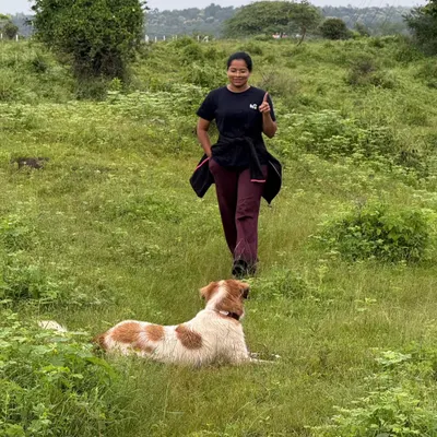 Leading a walk through a lush green field, with a happy and relaxed dog by my side. My adventure hikes are structured to let dogs be dogs, exploring nature while practicing calm behavior.