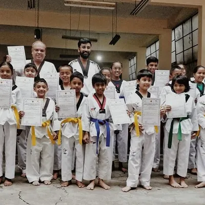 A group of our youngest students proudly displaying their new belts and certificates after a successful color belt exam. Their smiles show the joy of accomplishment.