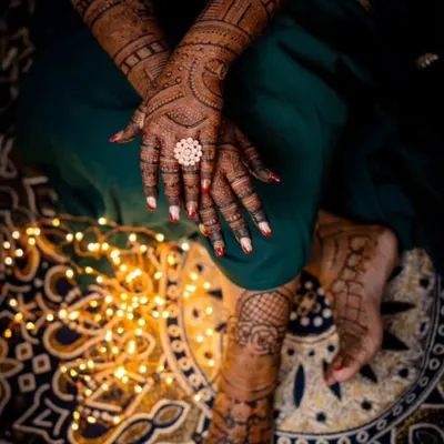 An artistic shot showing a bride's hands and feet adorned with mehandi. This demonstrates the full bridal package, ensuring the designs complement each other perfectly.