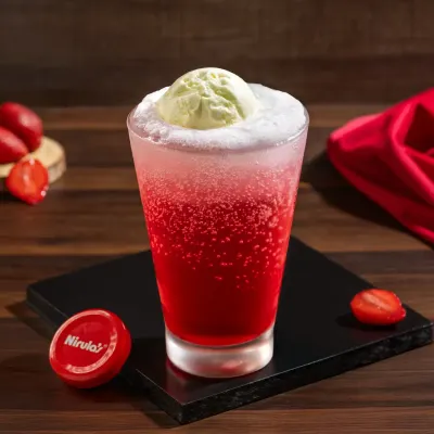 A vibrant strawberry ice cream soda, with a scoop of ice cream floating on top of a fizzy red drink.