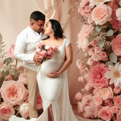 A romantic and dreamy maternity portrait with a beautiful floral backdrop. The soft lighting and the couple's tender embrace make this a truly timeless image.