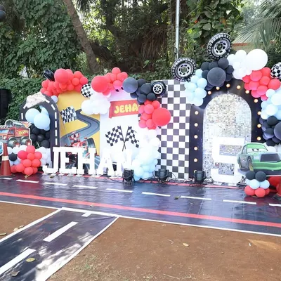 The main stage for a high-octane car-themed birthday party. I created a racetrack floor, a checkered flag arch, and used marquee letters for the birthday boy's name, Jehan, to make him feel like a racing star.
