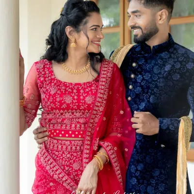 A picture-perfect couple at their engagement. The bride-to-be has a natural, glowing makeup look that enhances her features, paired with a beautiful red lehenga.