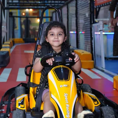 A young driver beams with excitement, ready to start her engine on our indoor go-kart track. The adjustable seats and safety harnesses ensure a perfect fit for kids.