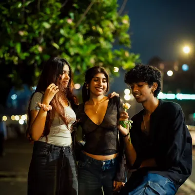 A candid moment between friends on a Mumbai street at night. The warm streetlights create an intimate atmosphere for this group portrait.