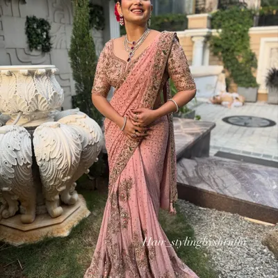 A full-length view of a client in a beautifully draped pink saree, paired with an elegant updo. This shows how I coordinate the hairstyle and saree draping for a cohesive look.
