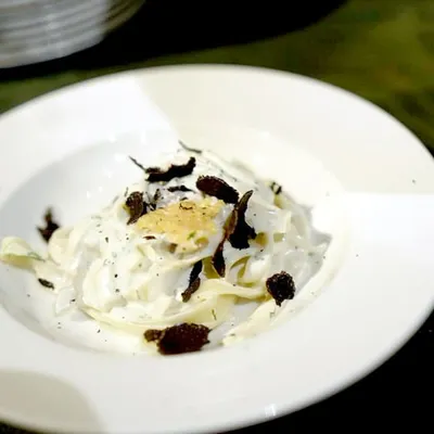 The final product of our Italian Pasta Studio. Freshly tossed fettuccine in a creamy Parmesan sauce, finished with generous shavings of French black truffle. A truly gourmet experience.