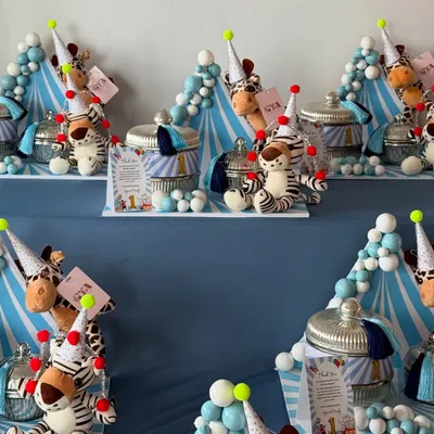 Step right up! A display of jungle-circus themed return favors for a first birthday, featuring plush animals in party hats and decorative jars.