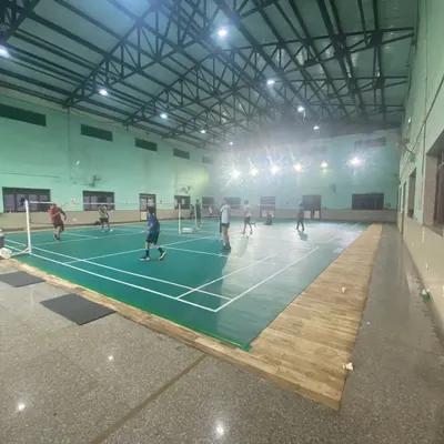 A wide view of our indoor badminton hall, showing the layout of our green synthetic courts. The high ceiling and professional lighting system ensure a great playing environment.