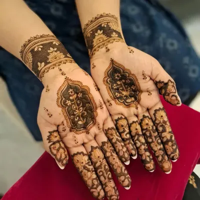 An elegant and modern henna design perfect for a wedding guest or festive occasion. This style features delicate floral work on the fingers and a beautiful architectural motif on the palm, leaving negative space for a contemporary feel.